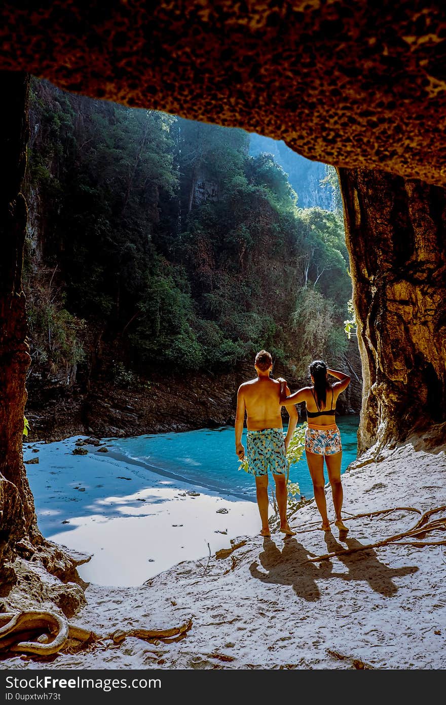 Hidden beach with huge cave near Koh Poda Island Krabi Thailand,men at a limestone cliff looking out over the secret