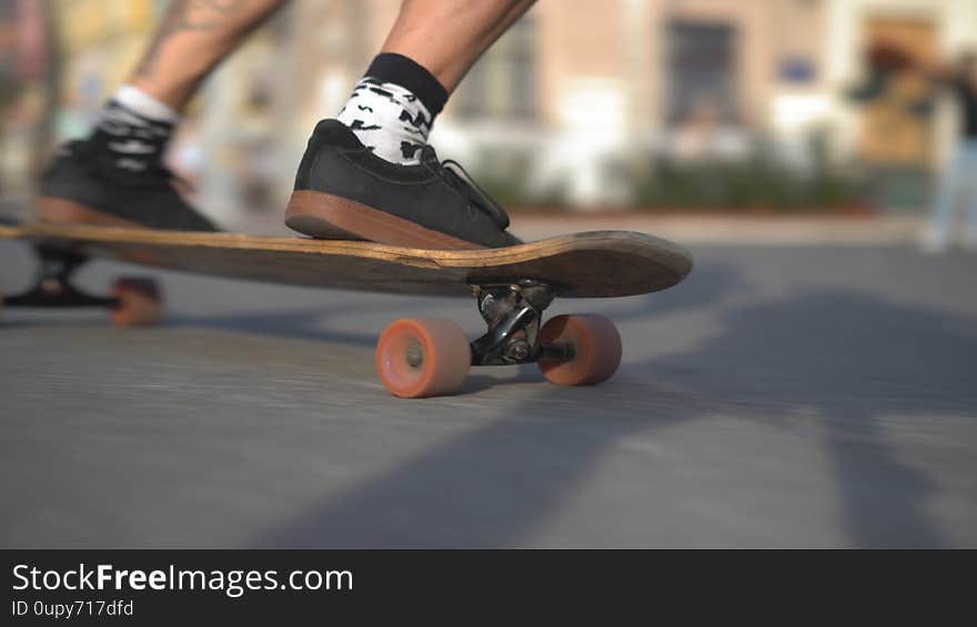 The legs of a light-skinned man rushing forward on a longboard. Motion Close-up concept.