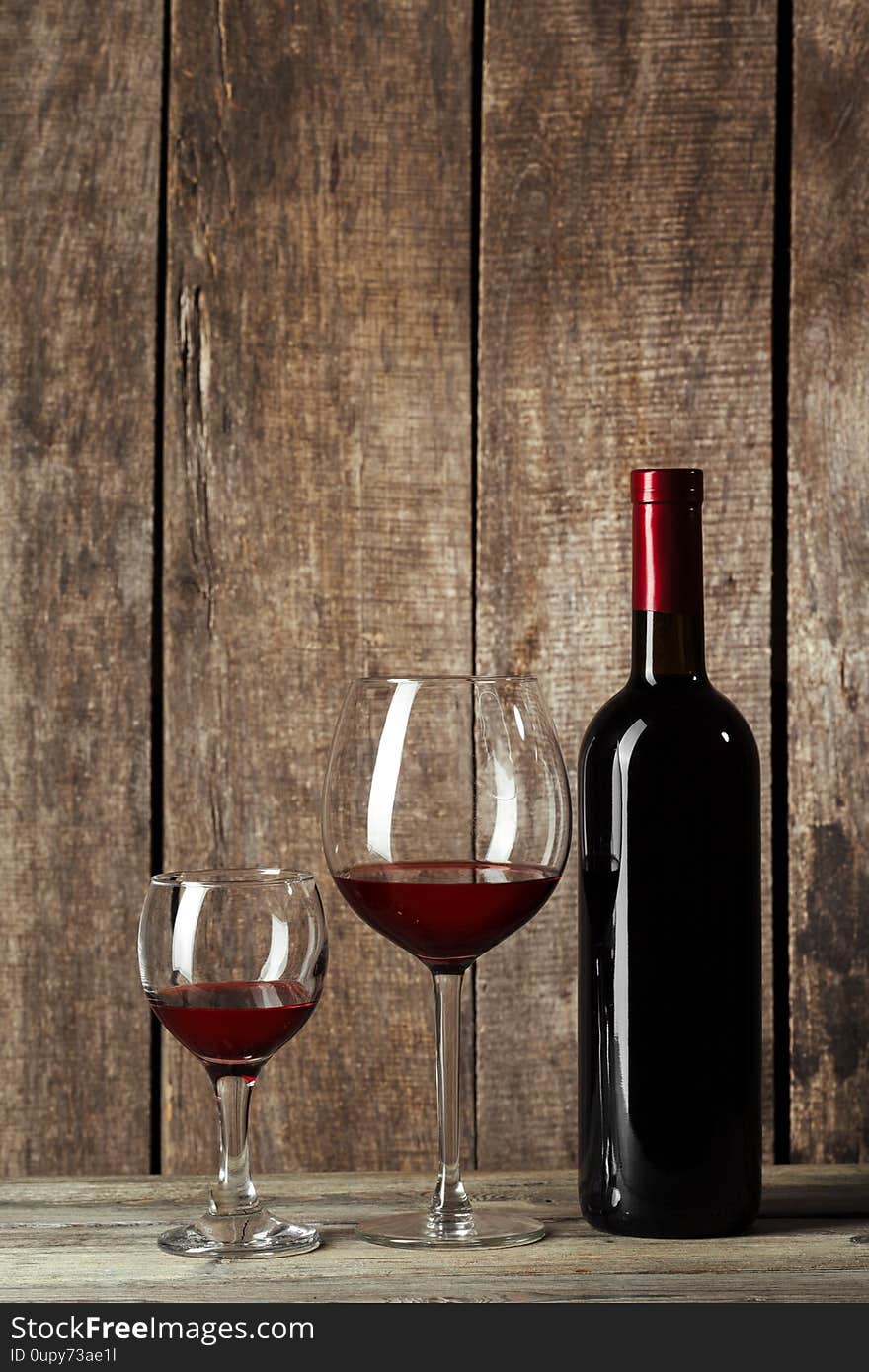 Glass And Bottle With Delicious Red Wine On Table Against Wooden Background. Creative Photo.