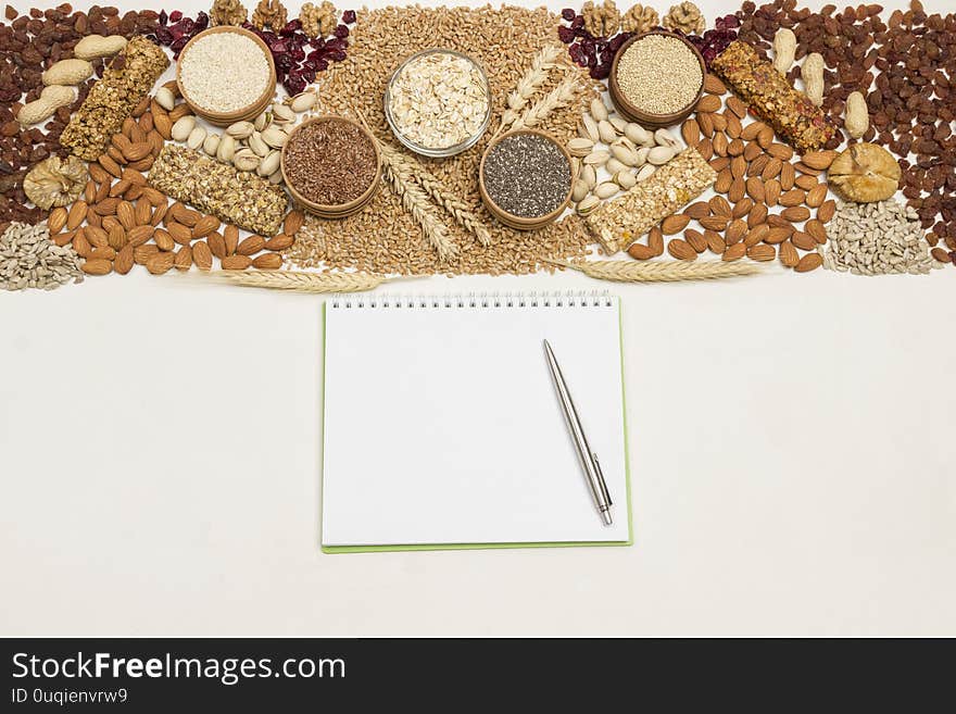 Balanced vegan snack, protein granola bar. Nuts, seeds, cereals notebook, pen on wooden background. Weigh less concept. Flat lay. White background