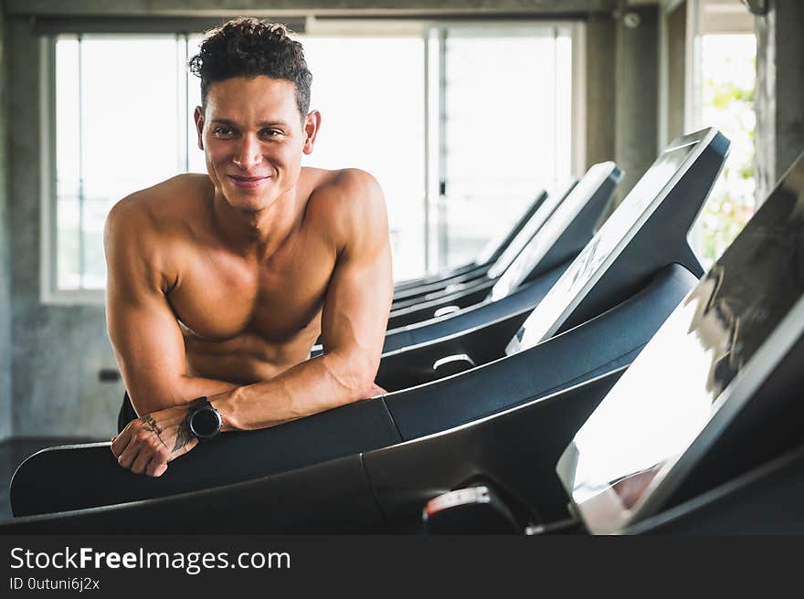 Young handsome man standing near treadmill. Themes about exercise for good health concept.