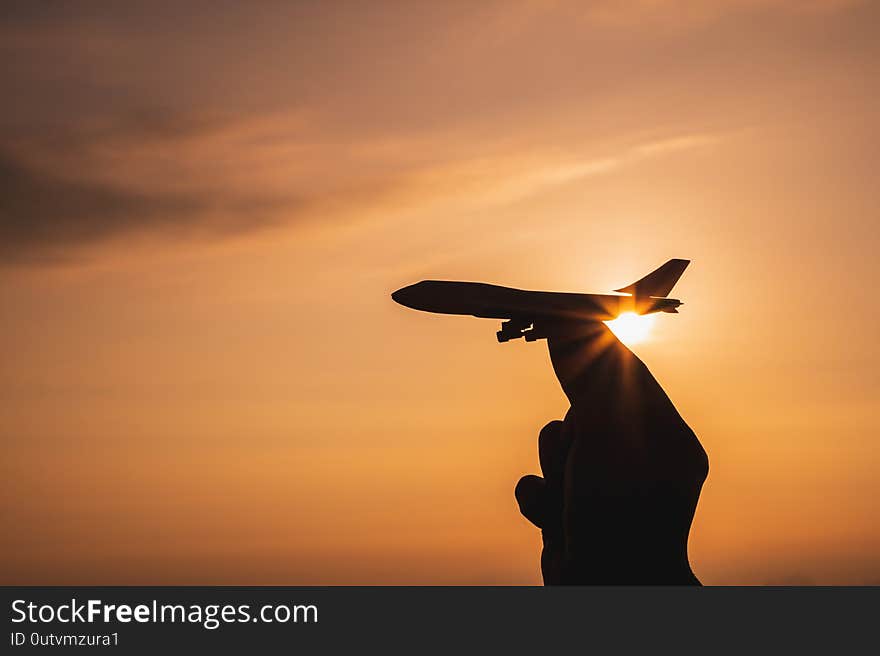 A hand holding a toy plane Go to the sky with sunset light.