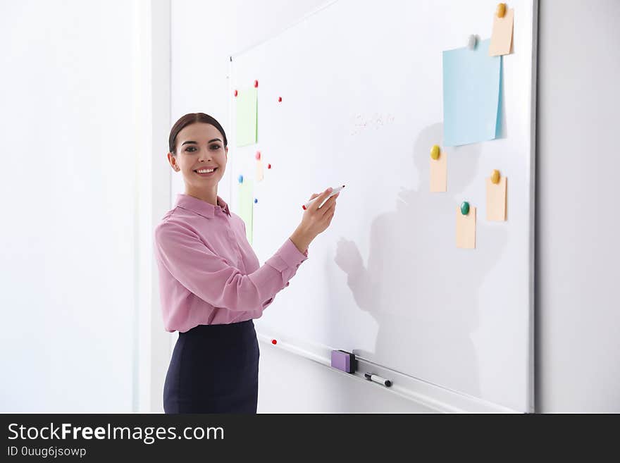 Young teacher writing on whiteboard in classroom