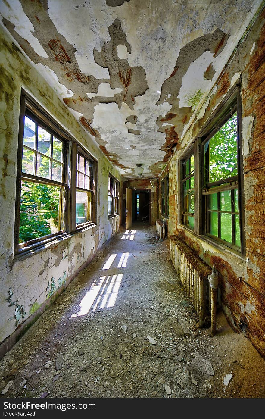 Abandoned desolate connecting interior hallway with windows of an institution. Abandoned desolate connecting interior hallway with windows of an institution