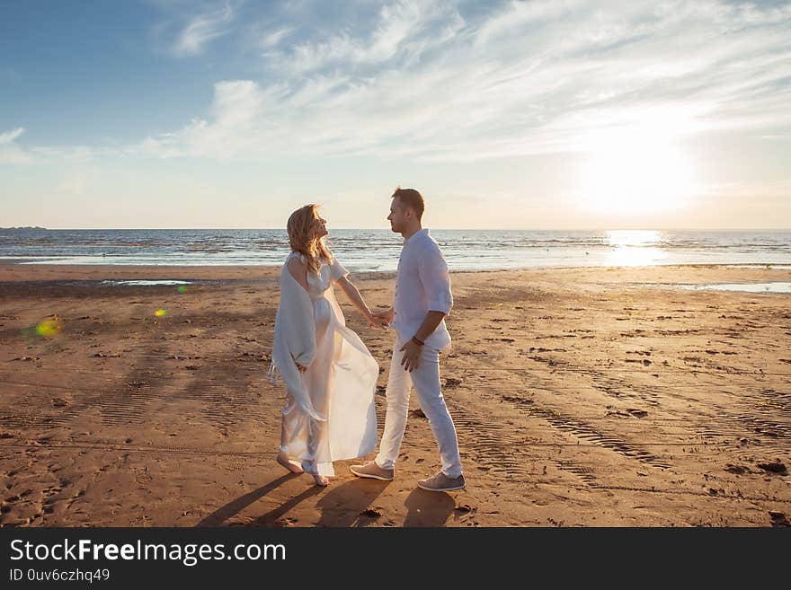 Love, waiting for the baby. Couple, pregnant woman and man, in white flying clothes, walk, hold hands, dance.