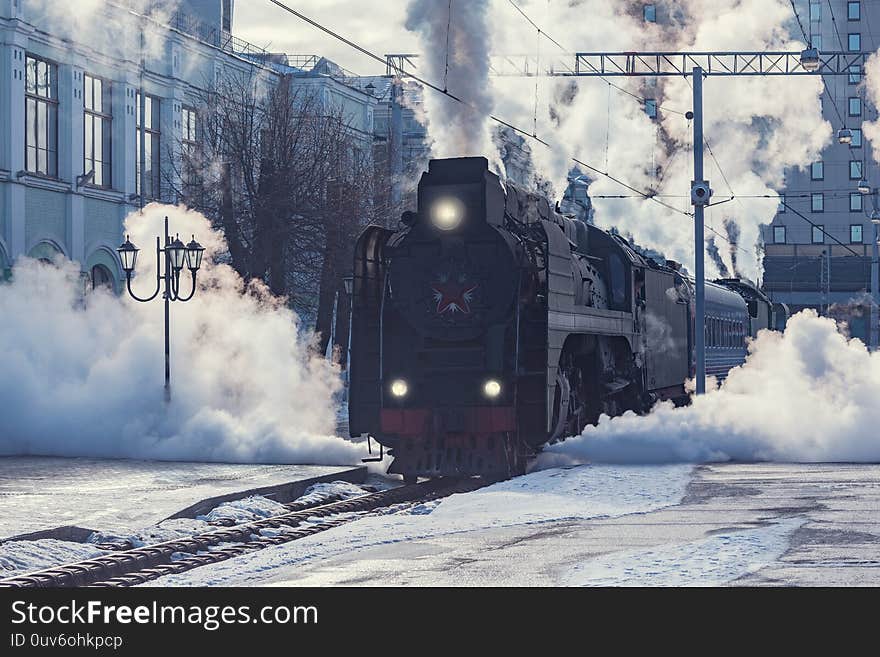 Retro steam train departs from the railway station at winter morning time. Retro steam train departs from the railway station at winter morning time.