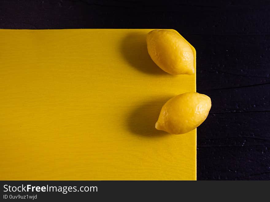 Minimalism photo of two yellow small fresh lemons soap with shadows on monochrome yellow and black background. Top view, copy space. Minimalism photo of two yellow small fresh lemons soap with shadows on monochrome yellow and black background. Top view, copy space.