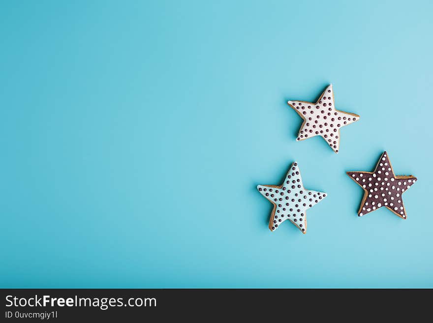 Close-up of three homemade glazed gingerbread cookies made in the form of stars on a blue background. Handmade cookies. Free space