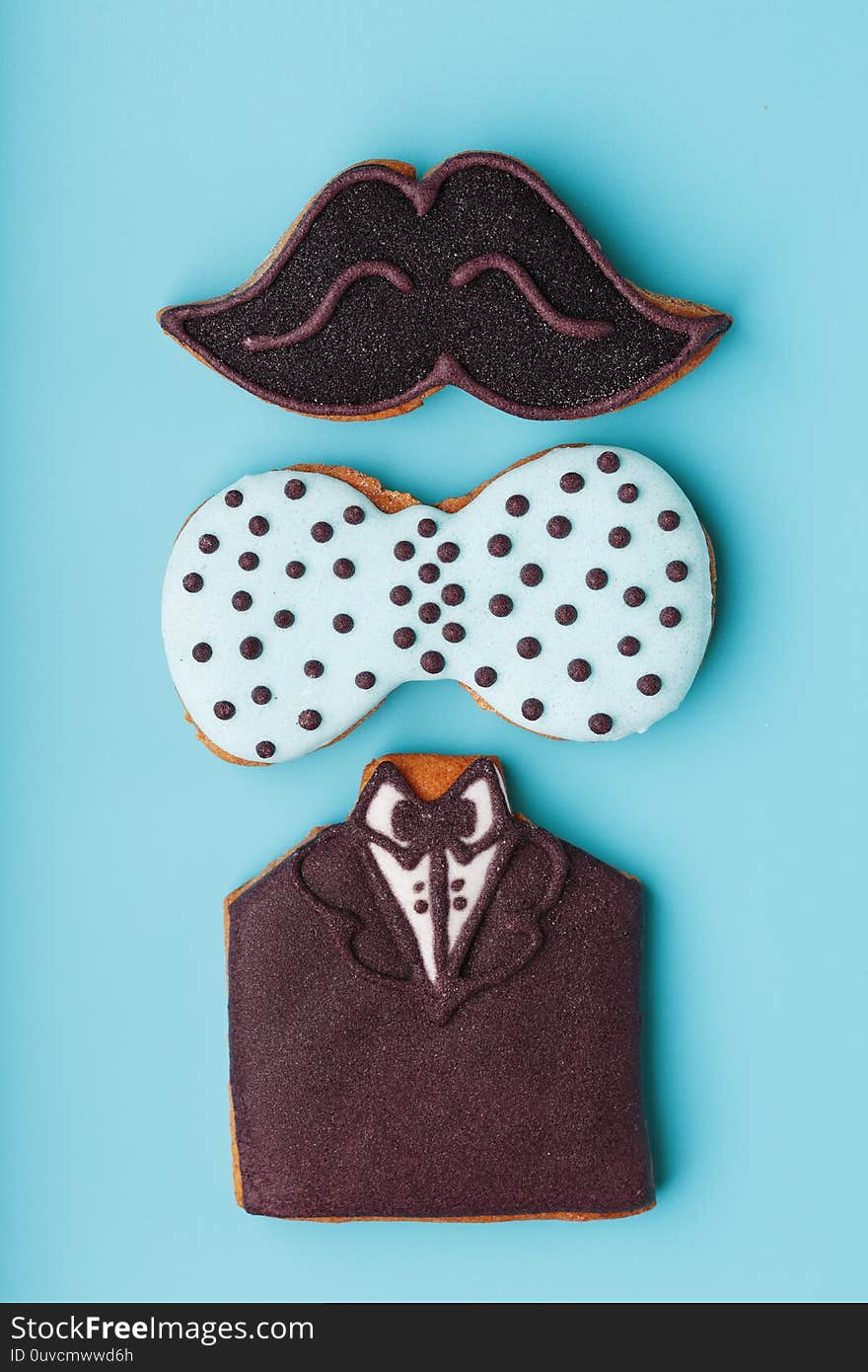 Glazed gingerbread in the form of a mustache, butterfly and tuxedo, men`s set on a blue background. Handmade cookies