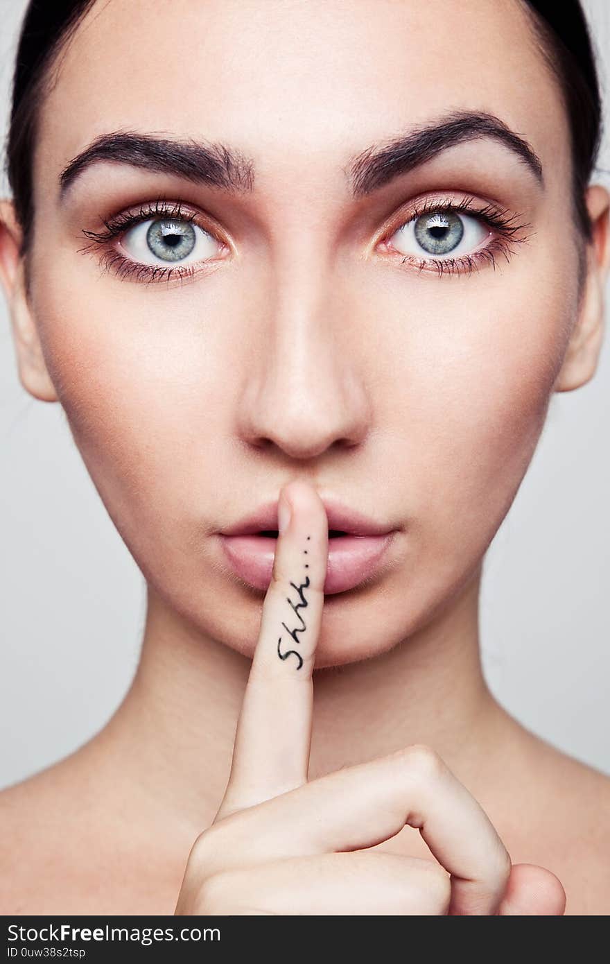 Portrait of a BEAUTIFUL Sensual brunette woman. Girl with word shhh on finger. Portrait of a BEAUTIFUL Sensual brunette woman. Girl with word shhh on finger