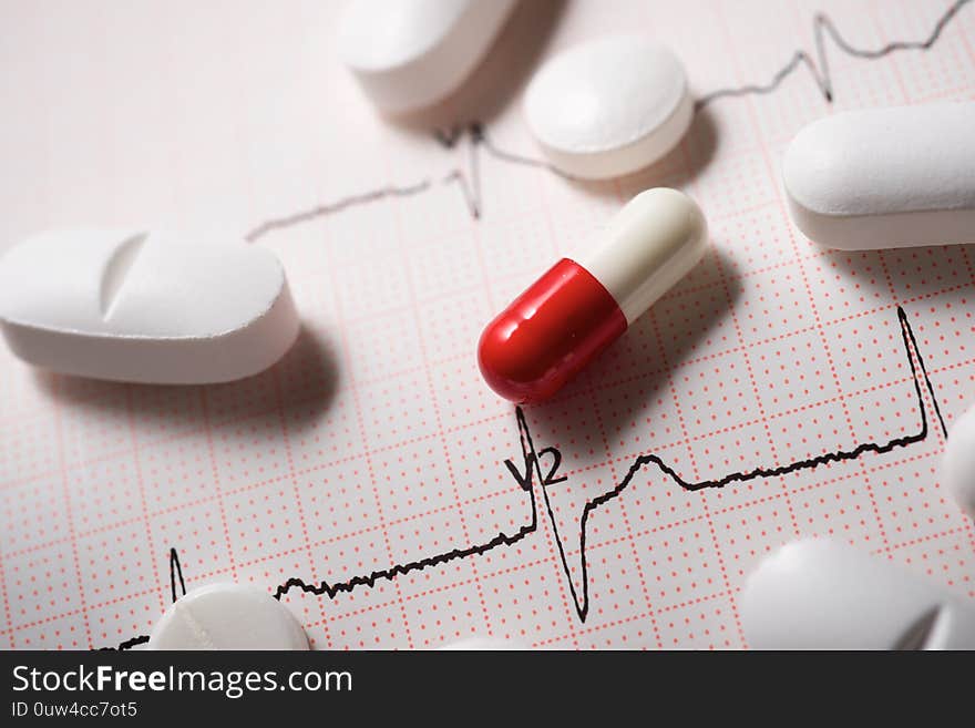 Close up of pills and an electrocardiogram in paper form. Close up of pills and an electrocardiogram in paper form