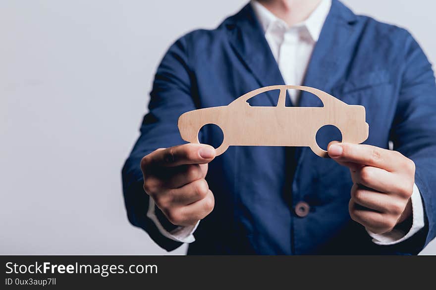 Man proposing signing a car insurance policy, the agent is holding the wooden car model. Car insurance concept. Man proposing signing a car insurance policy, the agent is holding the wooden car model. Car insurance concept.