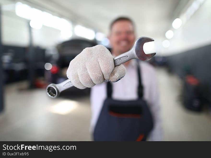 Close-up view of garage professional mechanic holding wrench. Macro shot of worker with special equipment to repair transport facility. Service station concept. Close-up view of garage professional mechanic holding wrench. Macro shot of worker with special equipment to repair transport facility. Service station concept