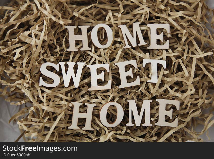 Letters sitting on brown shredded paper forming the words Home sweet home