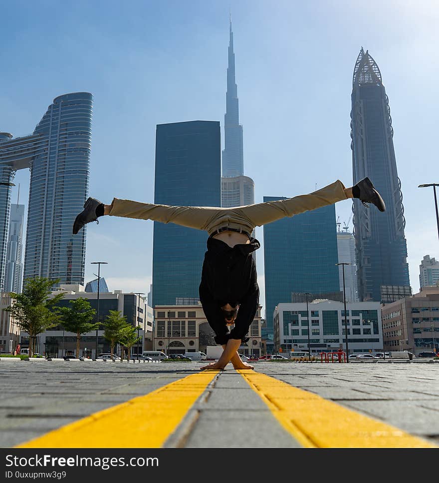 Acrobat keep balance one the hands with blurred Dubai cityscape. Concept of modern, business and unlimited possibility