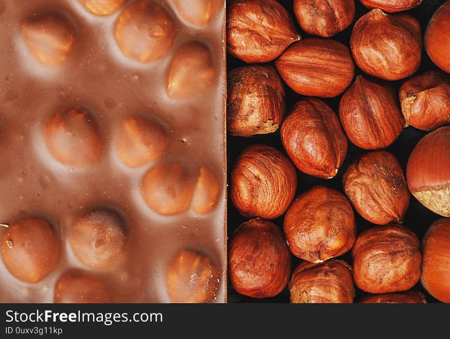 Chocolate with hazelnuts, nuts in a shell in the form of a solid texture. Dessert-milk chocolate with nuts. Confectionery. Full screen top view