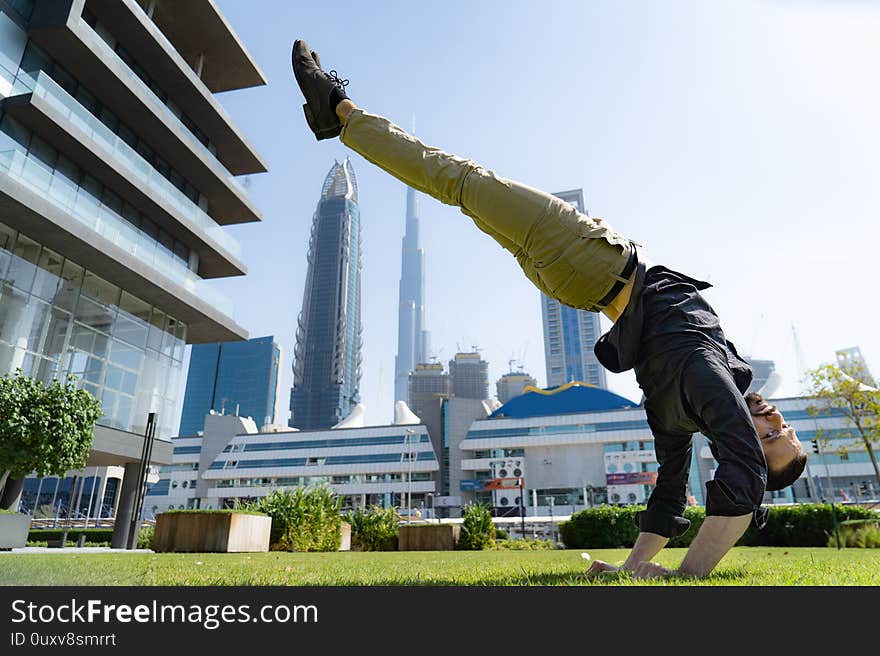 Acrobat keep balance one the hands with blurred Dubai cityscape. Concept of modern, business and unlimited possibility