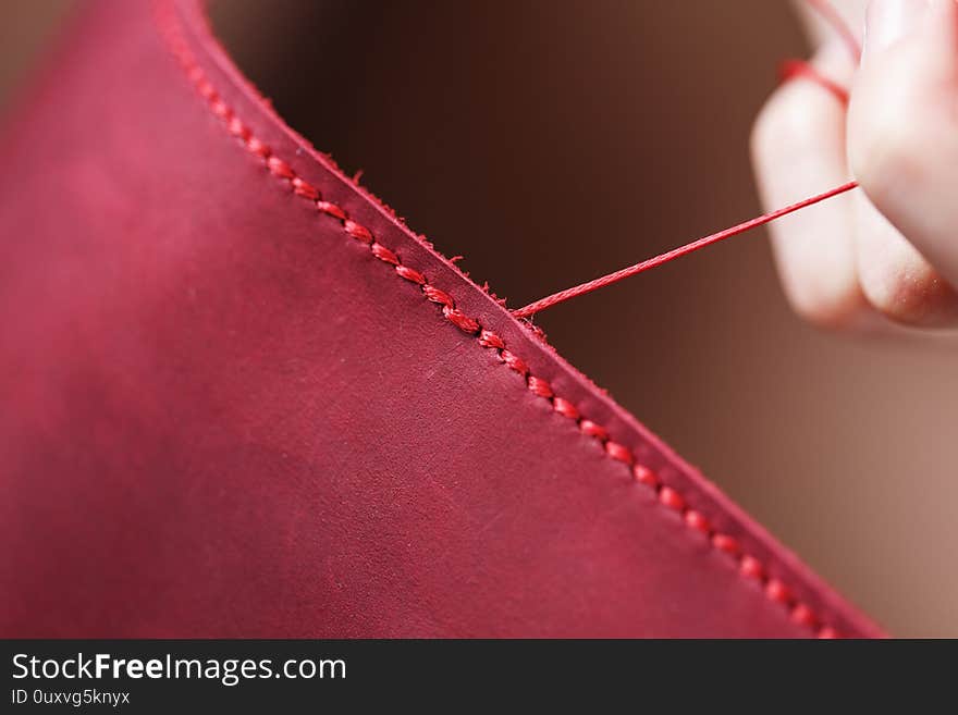 Conceptual profession of a Tanner. The woman`s hands closed around the needle and thread