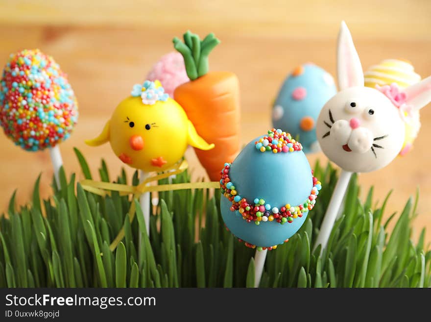 Delicious sweet cake pops in green grass, closeup. Easter holiday