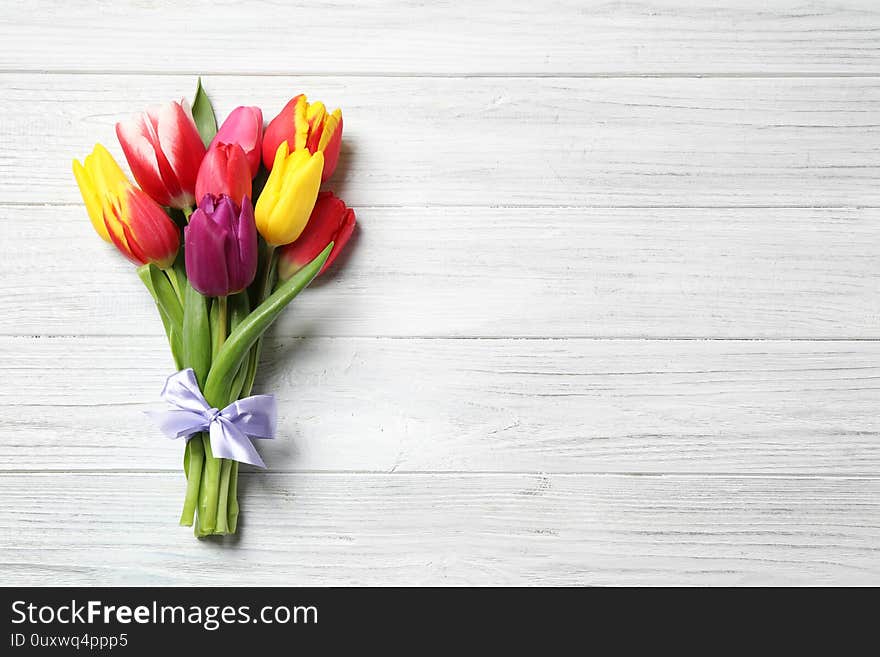 Beautiful spring tulips on white wooden table, top view. Space for text