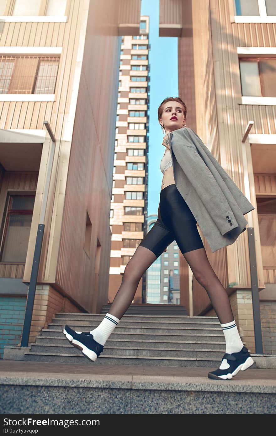 Young stylish woman wearing coat walking outdoors urban background looking aside pensive full body shot in motion. Young stylish woman wearing coat walking outdoors urban background looking aside pensive full body shot in motion