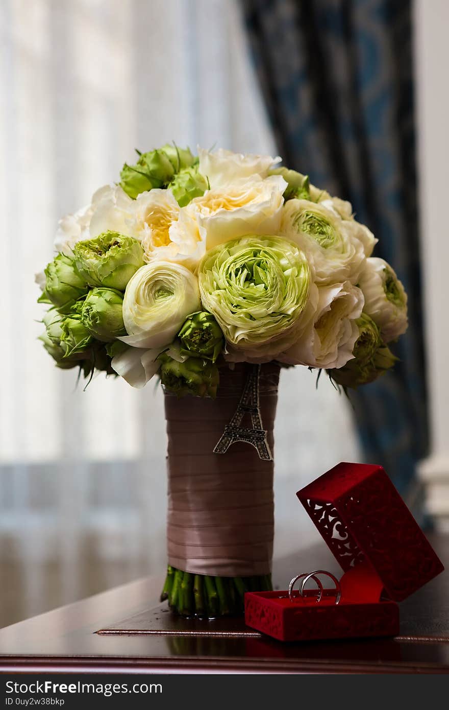 Bouquet of white roses and silver wedding rings.