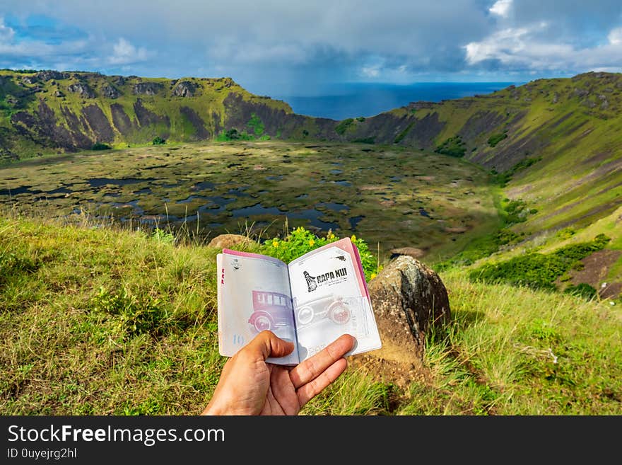 Showing passport with Rapa Nui stamp to Rano Kau volcano crater. Showing passport with Rapa Nui stamp to Rano Kau volcano crater