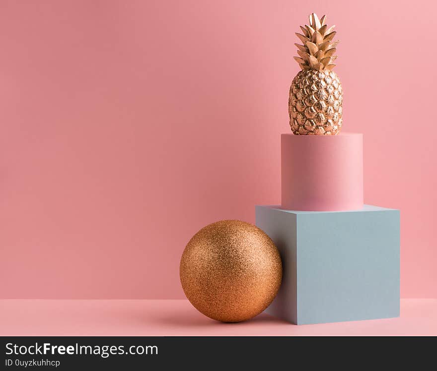 Golden pineapple, glitter ball, teal cube and pink round box on pink background. Minimalistic luxury design. Golden pineapple, glitter ball, teal cube and pink round box on pink background. Minimalistic luxury design.