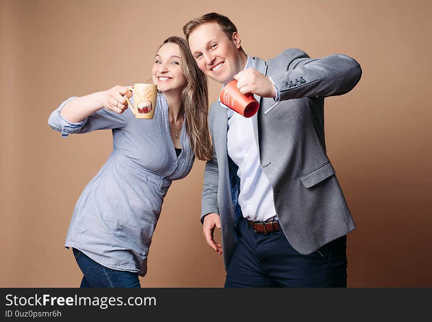 Two beautiful lovers stands with cups and smiles