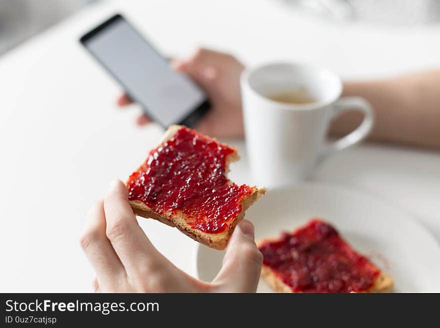 The Guy Watches The News On The Phone During Breakfast