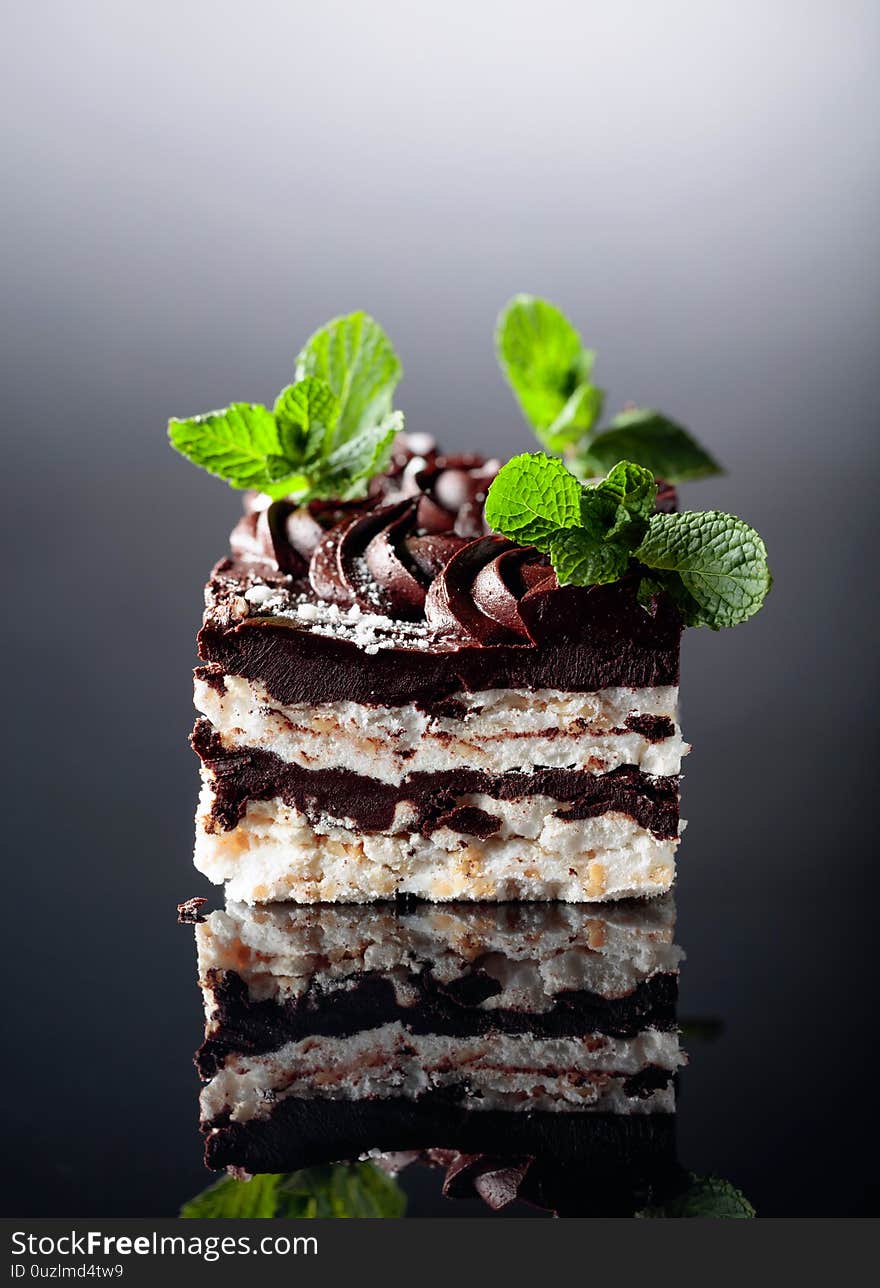 Delicious chocolate cake with mint on a black reflective background