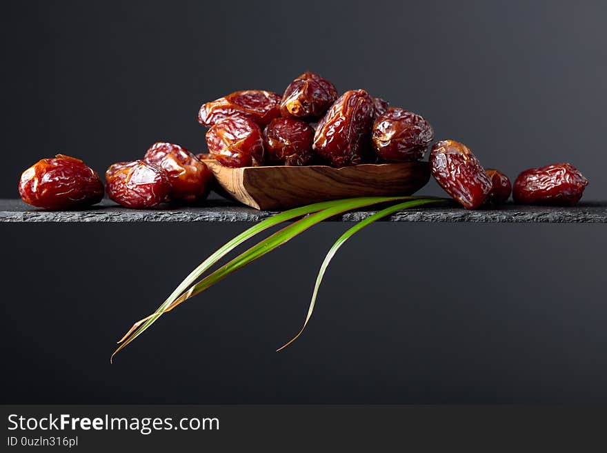 Closeup sweet dried dates in wooden dish. Copy space