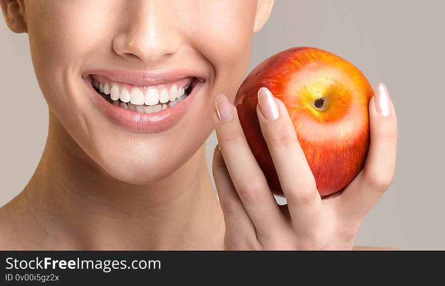 Toothcare. Unrecognizable Girl With Perfect Healthy Teeth Holding Red Apple And Smiling Posing Over Beige Studio Background. Panorama, Cropped. Toothcare. Unrecognizable Girl With Perfect Healthy Teeth Holding Red Apple And Smiling Posing Over Beige Studio Background. Panorama, Cropped