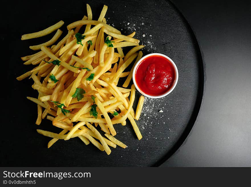 Chips fries and ketchup on a dark background. Top view, Unhealthy food.