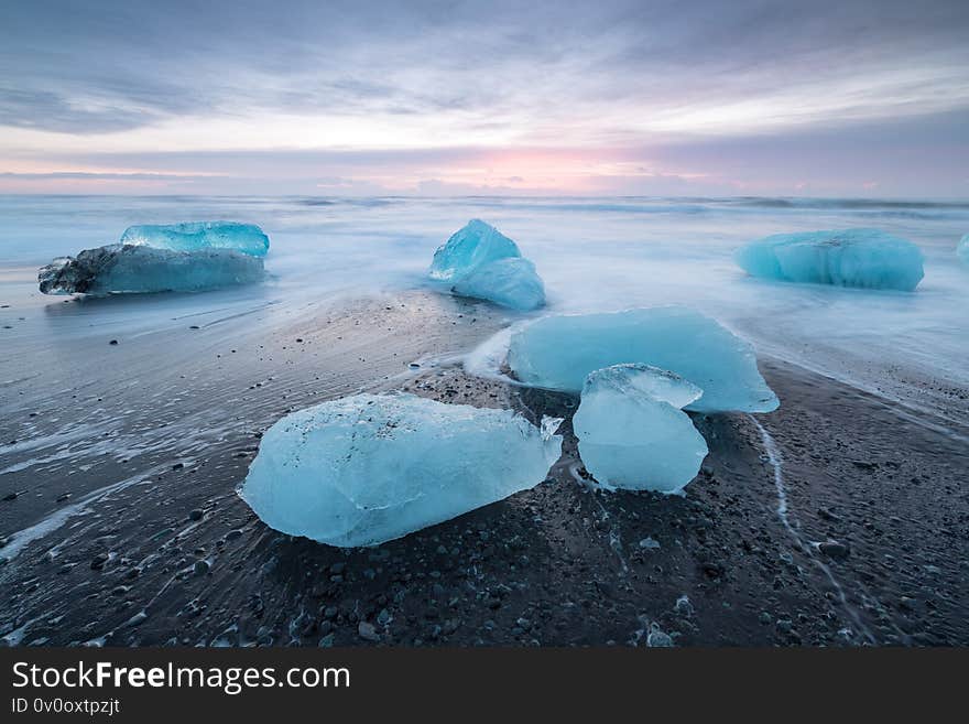 Beautiful sunset over famous Diamond beach, Iceland. This sand lava beach is full of many giant ice gems, placed near glacier lago