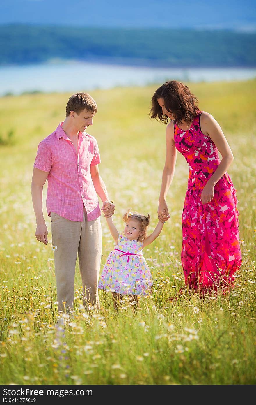 Happy young family with children having fun outdoors. Father, mother and child daughter spending time in nature on a summer day. Enjoying time together.