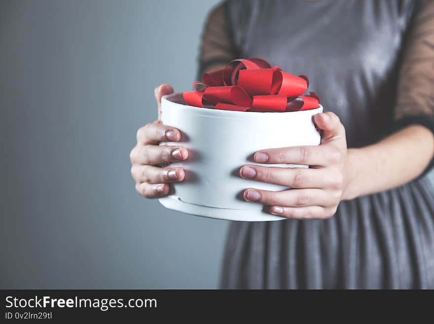 Woman hand white gift box on grey background. Woman hand white gift box on grey background