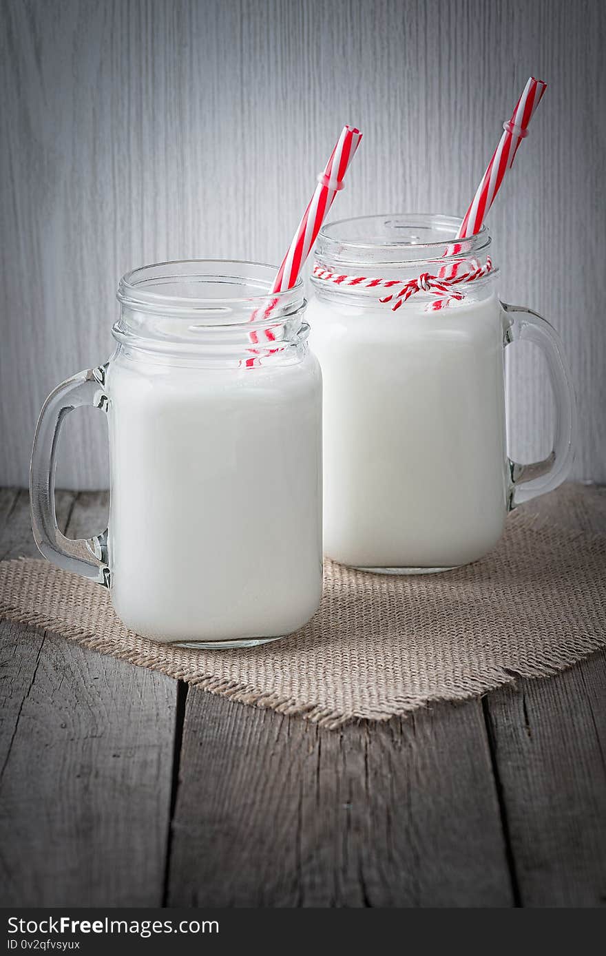 Glass cups with milk on a wooden rustic background.