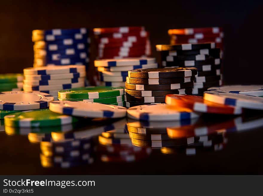 Colorful poker chips on reflecting surface close up.