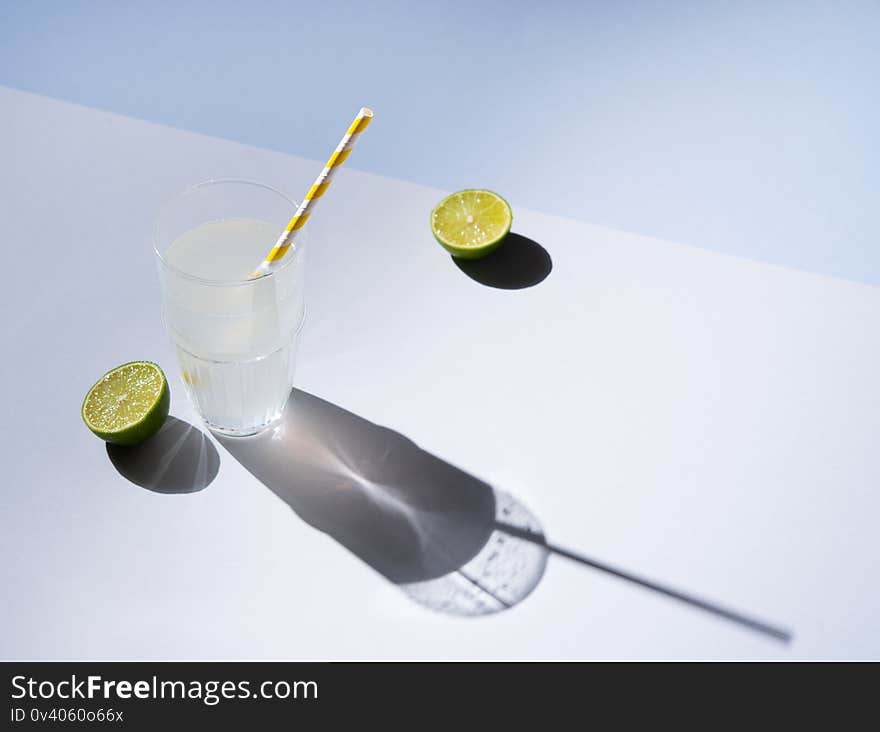 A glass of fresh  lime lemonade on a gray blue background with hard shadows