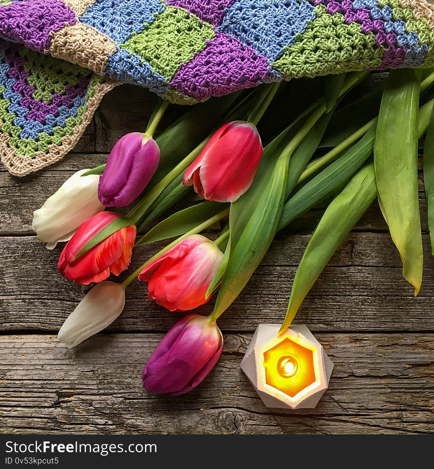 Multi-colored tulips on a dark wooden substrate.