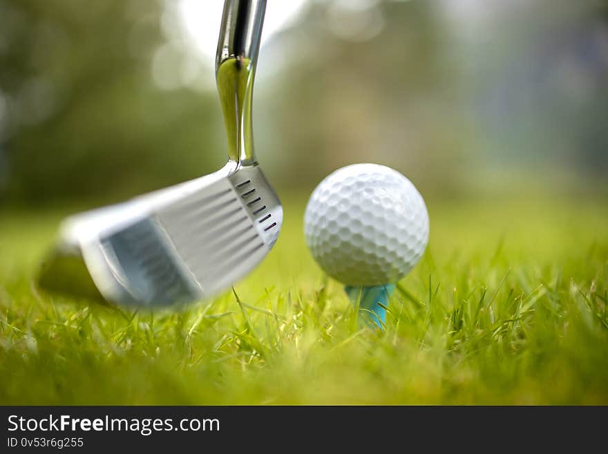 Golf club and ball on tee in front of driver. Golf club and ball on tee in front of driver