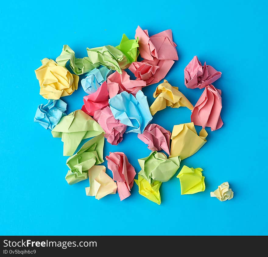 Crumpled multi-colored paper stickers, top view, blue background