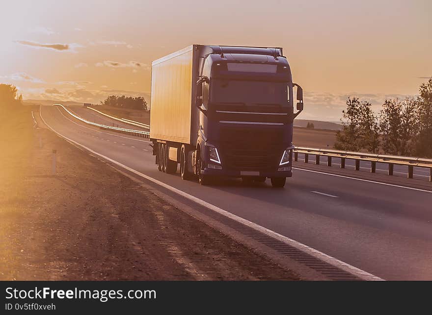 truck moves along a suburban highway at sunset lit by the sun