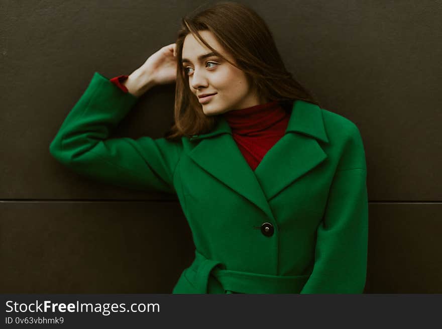 Beautiful fashion model in autumn green clothes on background. Sexy lady in elegant coat.