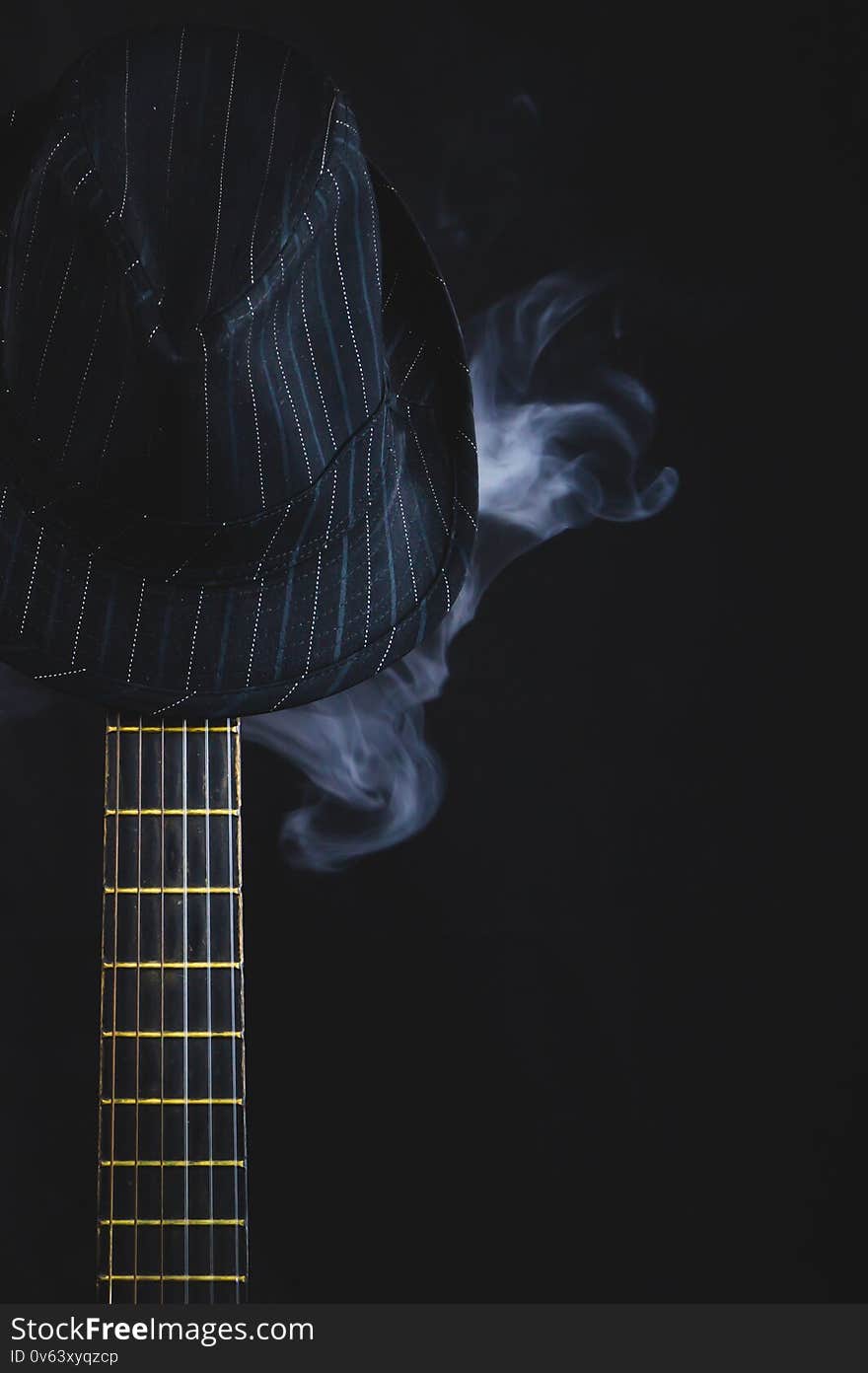 Smoking hat hangs on the guitar fretboard. acoustic musical instrument. strings on the guitar neck close up