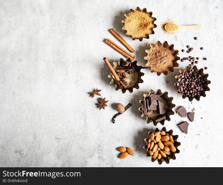 Baking ingredients: brown sugar, cocoa, almond, dark chocolate and spices on a gray marble background. Top view. Copy space