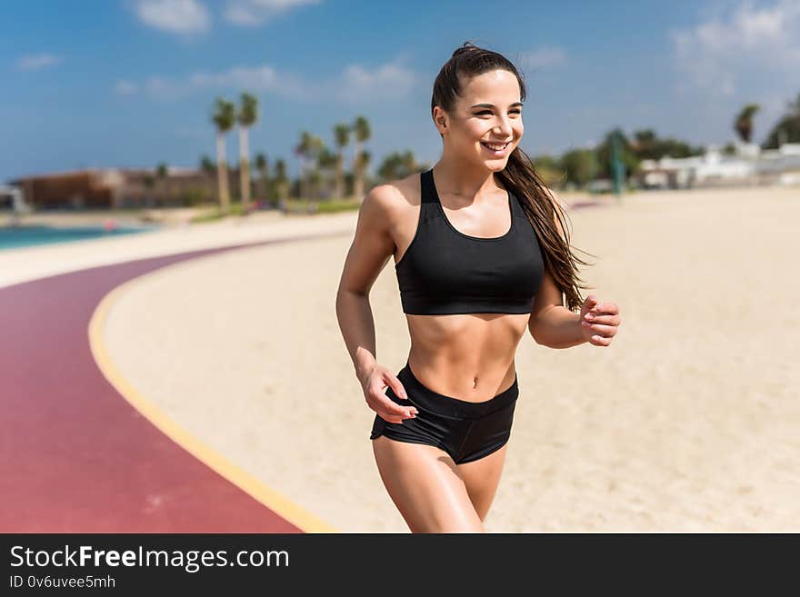 Beautiful sportive woman running along beautiful sandy beach, healthy lifestyle, enjoying active summer vacation near the sea