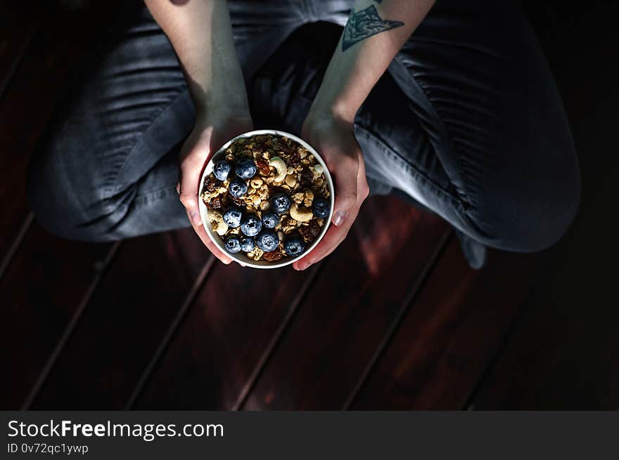 Breakfast healthy eating, hands holding cup with granola and berries.