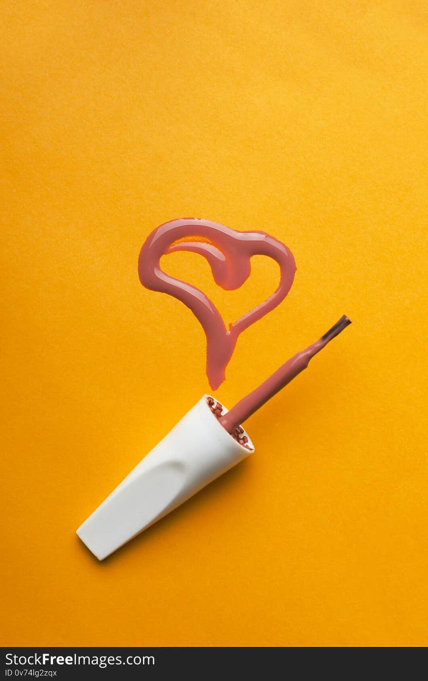 Vertical shot.Top view of brush for nail art and heart shape made of spilled nail polish background, beauty, bright, brush, care